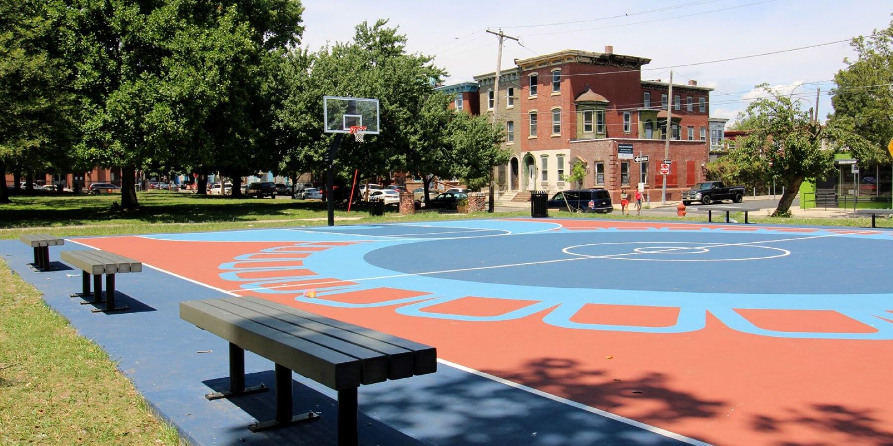 blue and red outdoor, open basketball court in an urban neighborhood