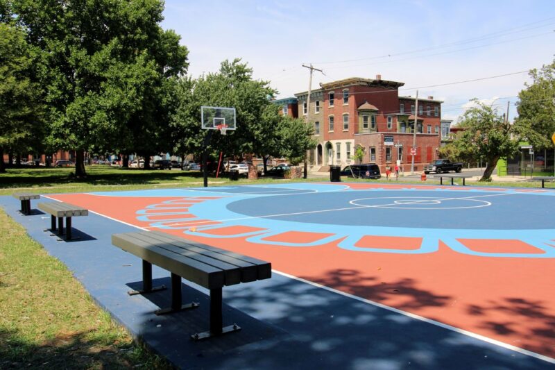 blue and red outdoor, open basketball court in an urban neighborhood